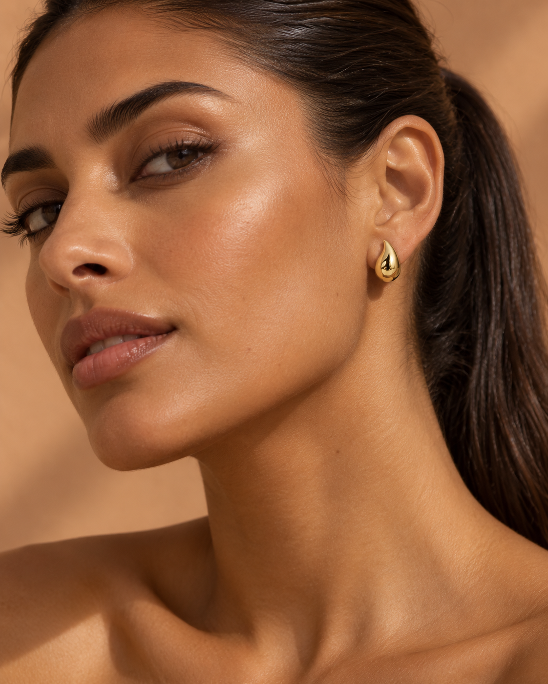Puce goutte en or jaune 9 carats portée par une femme brune à la peau mate