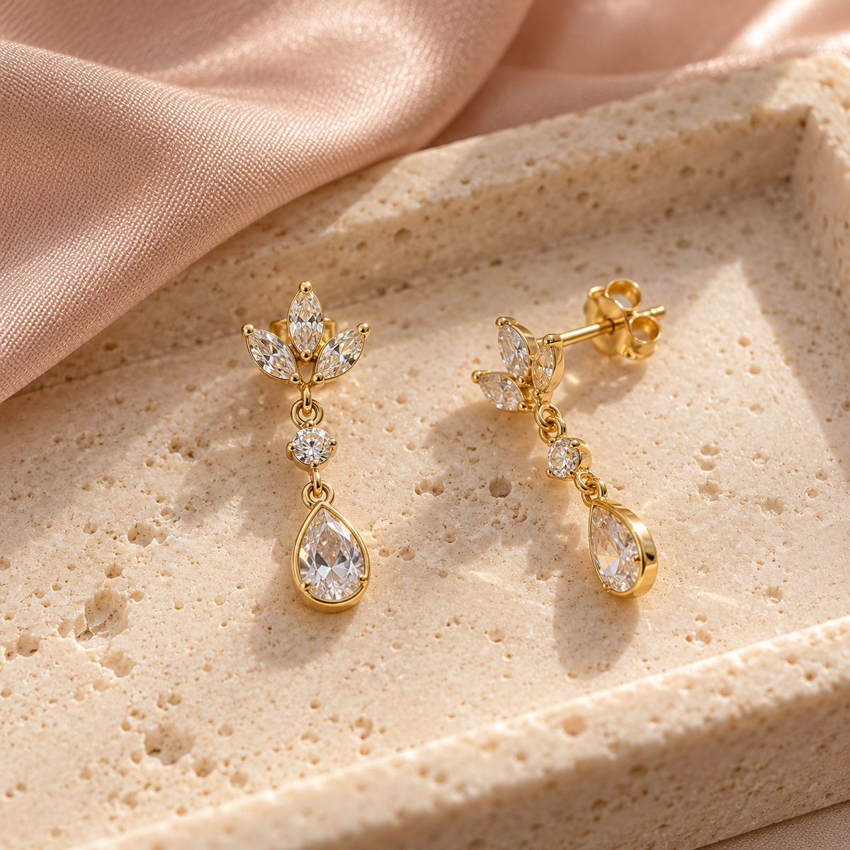 Boucles d’oreilles pendantes feuillage et goutte posées à plat sur pierre claire