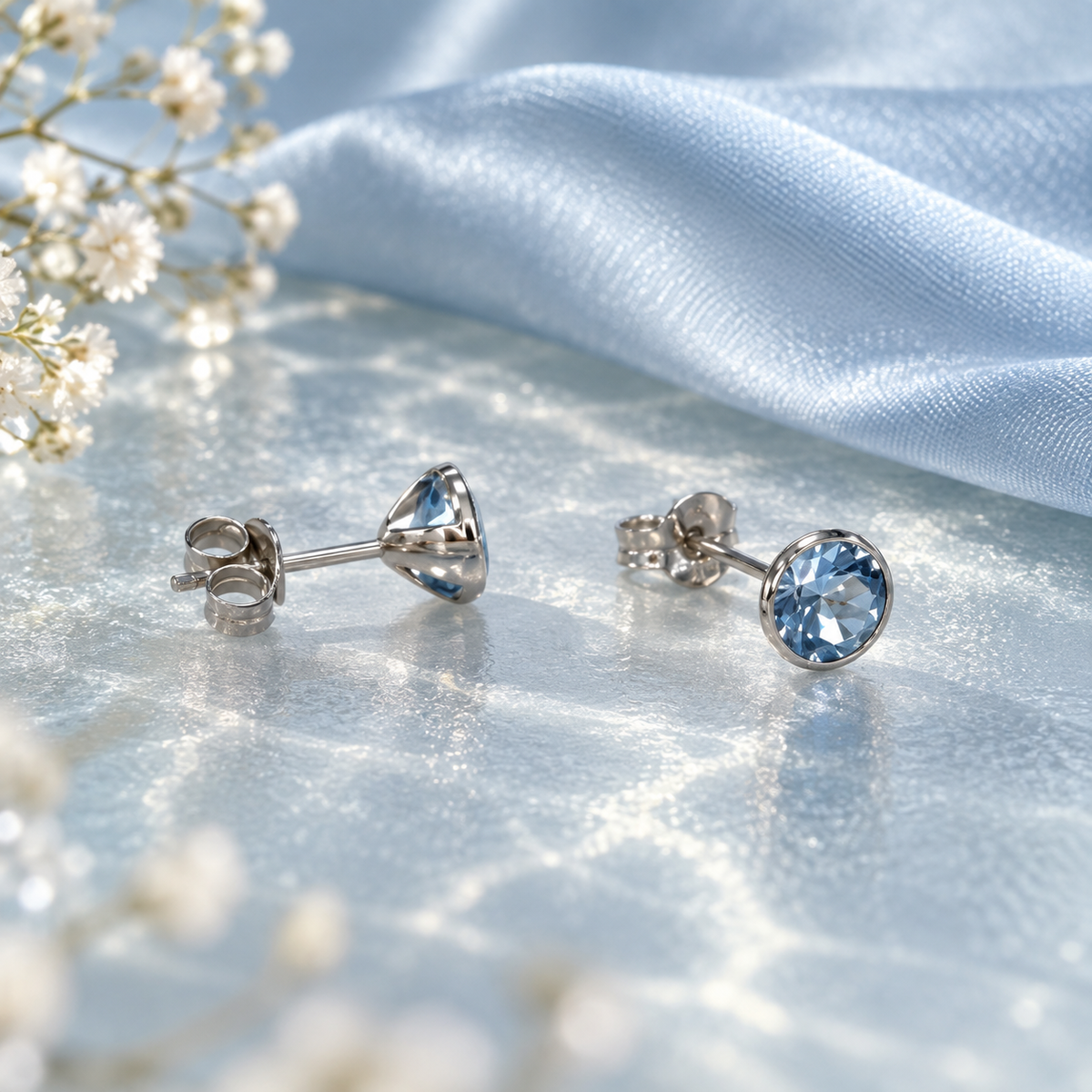 Puces topaze bleue en or gris 9 carats posées à plat sur un décor bleu