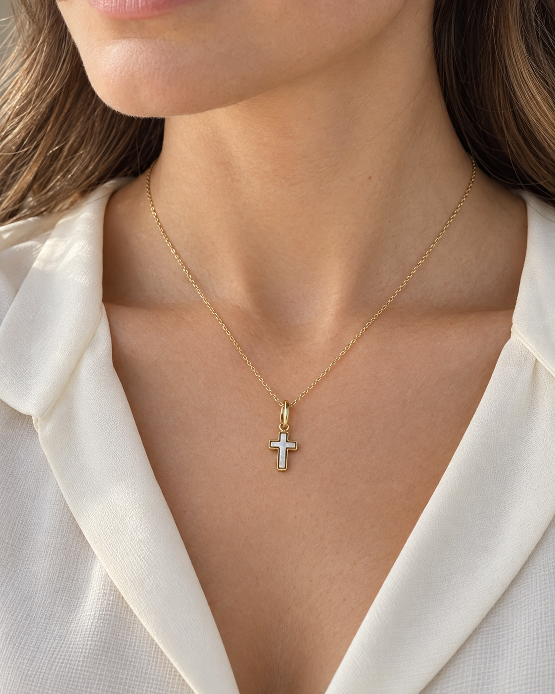Pendentif croix en nacre et or jaune 9 carats porté sur une chaîne par une femme